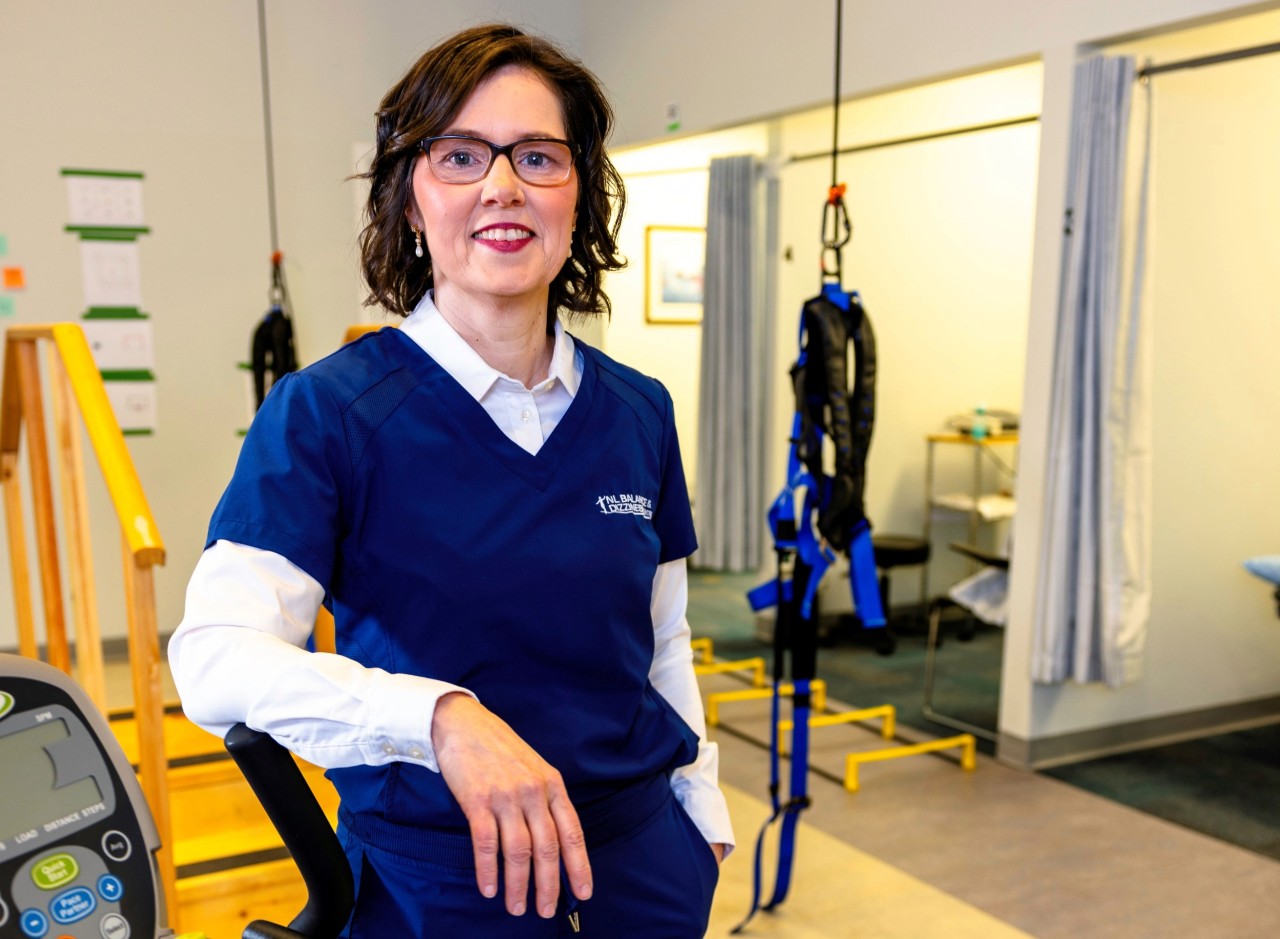 Physiotherapist Kim Furlong is standing in a clinic leaning on a piece of treatment equipment.