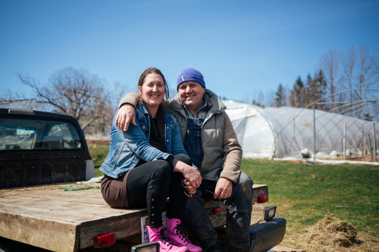 The Oultons sit close together on the back of a pick up truck on a sunny spring day at the farm.