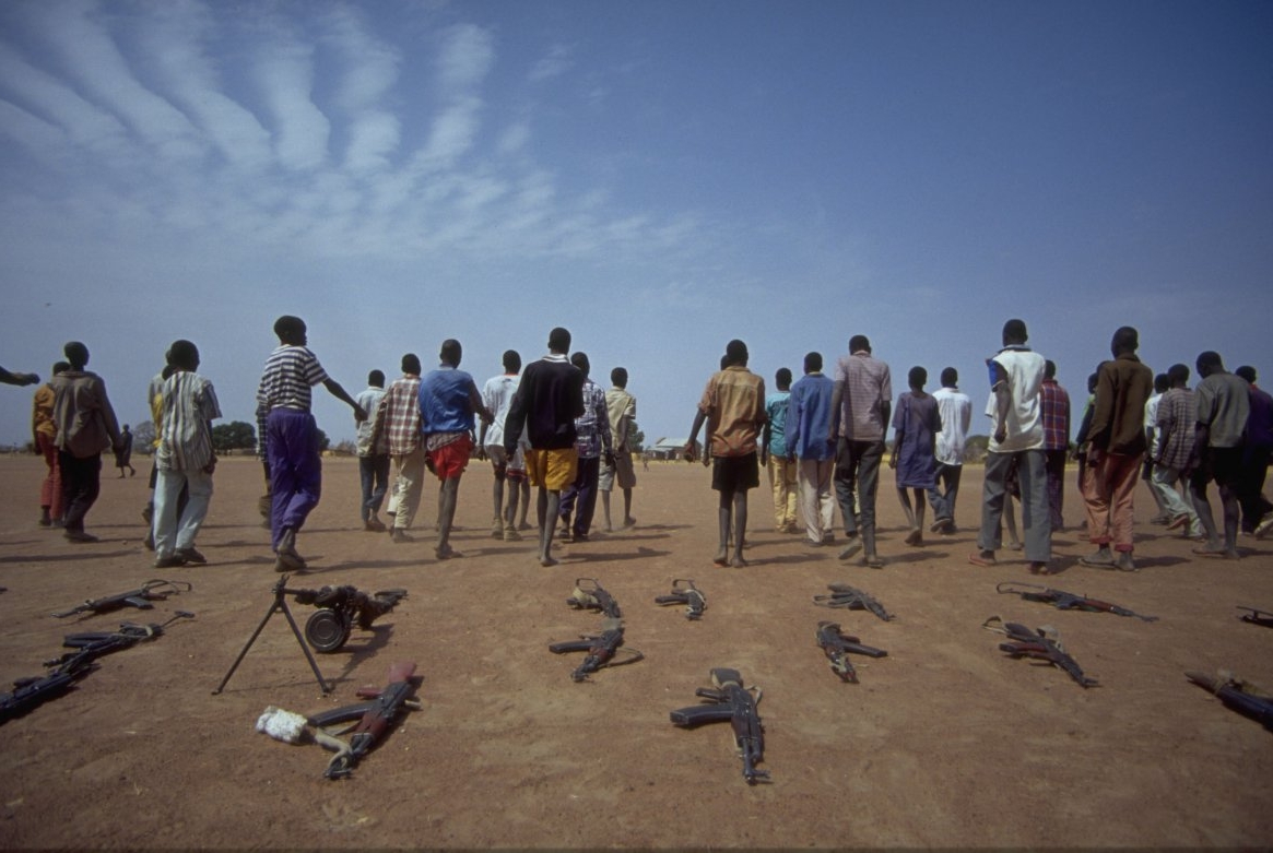 A group of people walking away from guns that have been laid on the ground