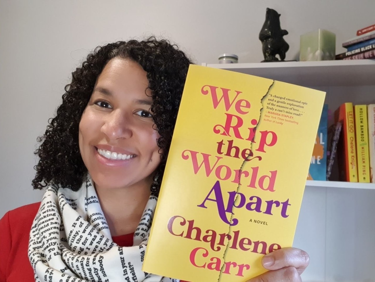 Carr holds up one of her books with a bookshelf in the background.