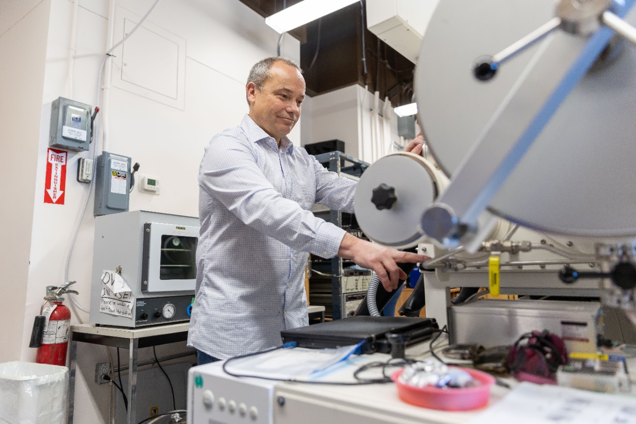 A researcher operates equipment resembling a large wheel and a smaller wheel