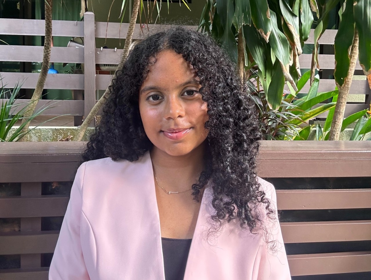 A heashot of a woman wearing a black shirt and pink blazer 