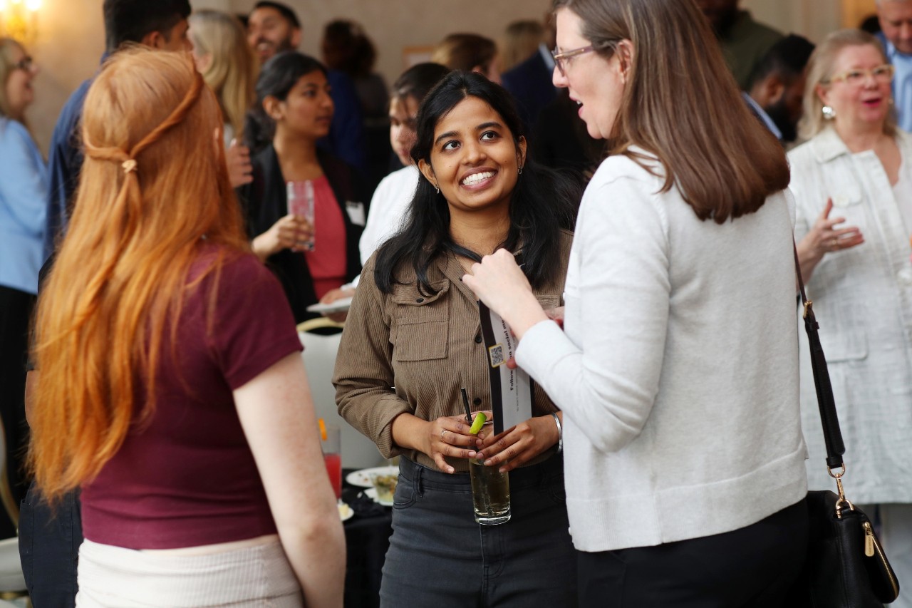 A diverse crowd of attendees casually mingle at a social event.