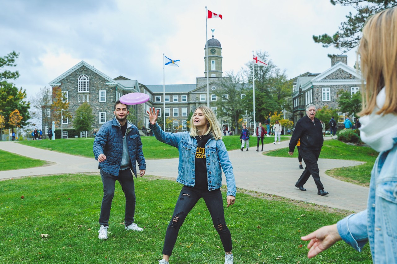 Students on quad playing frisbee in front of the Henry Hicks Building.