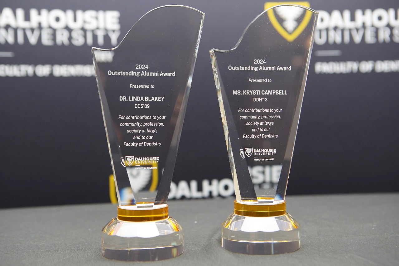 Two glass awards atop a table with the names of the winners etched on them displayed at an event.