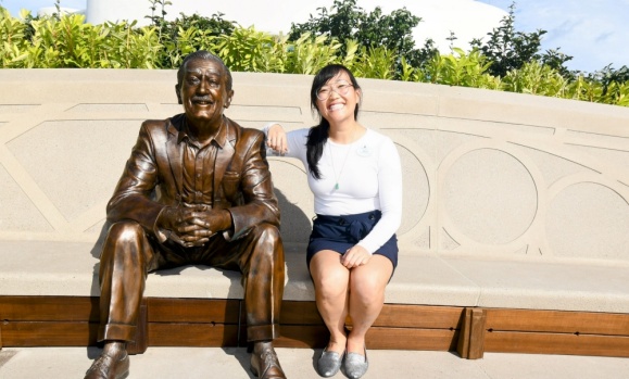 Park sitting next to a stature of Walt Disney.