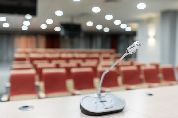 Microphone in front of a room full of empty seats.