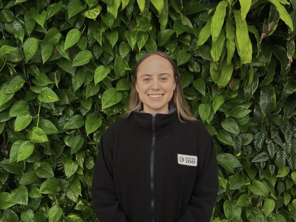 Gabrielle Clark standing against a backdrop of green leaves.