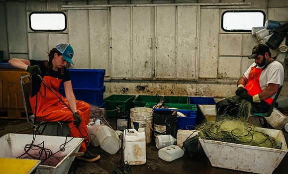 Hannah Harrison picks fish from a gillnet on a Great Lakes commercial fishing tug alongside fisherman Brett Martin. 