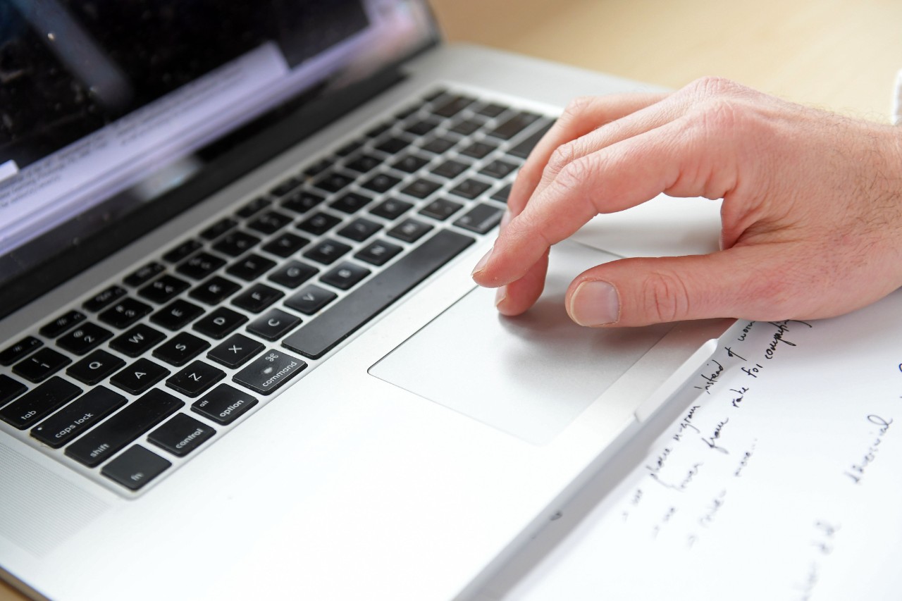 Close up of a Caucasian hand scrolling on a laptop touchpad.
