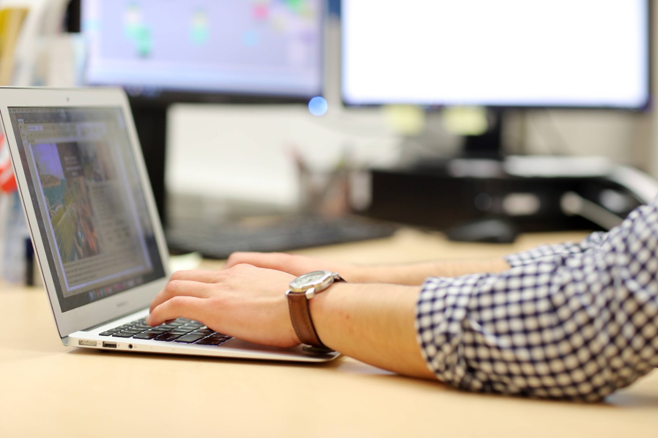 Person wearing watch writing on a laptop.