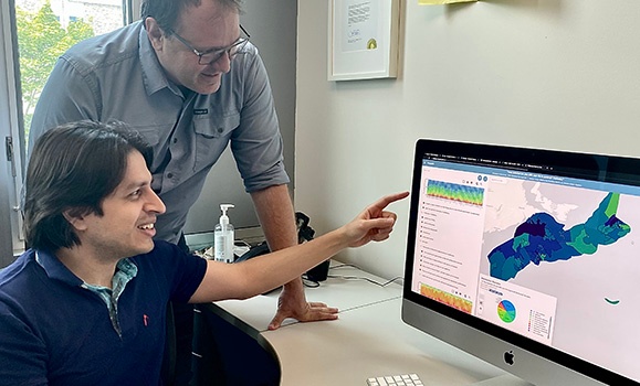 two male researchers pointing at a computer screen showing virtual new wellbeing tool