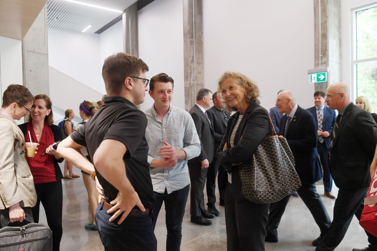 A woman chats with two young men during an event