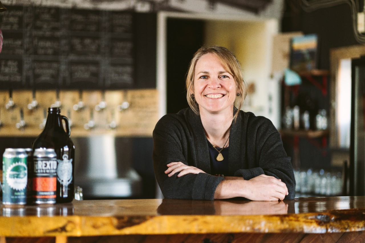 Mills leaning on the bar, smiling at the brewing company.