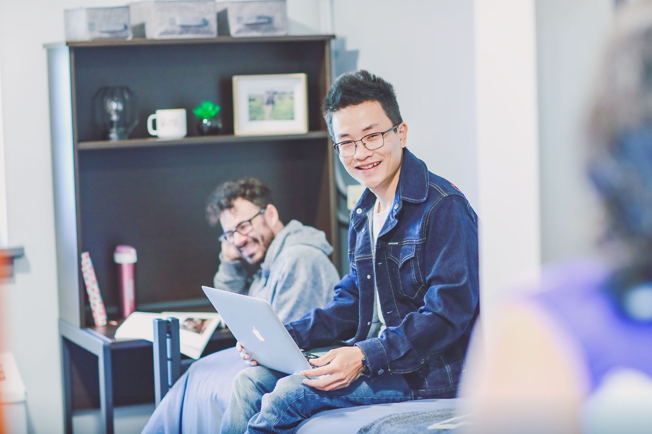 Students in residence room smiling and collaborating.