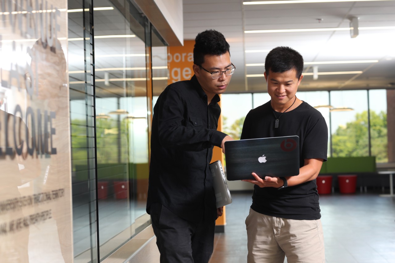 Two people looking at one laptop inside the student learning commons