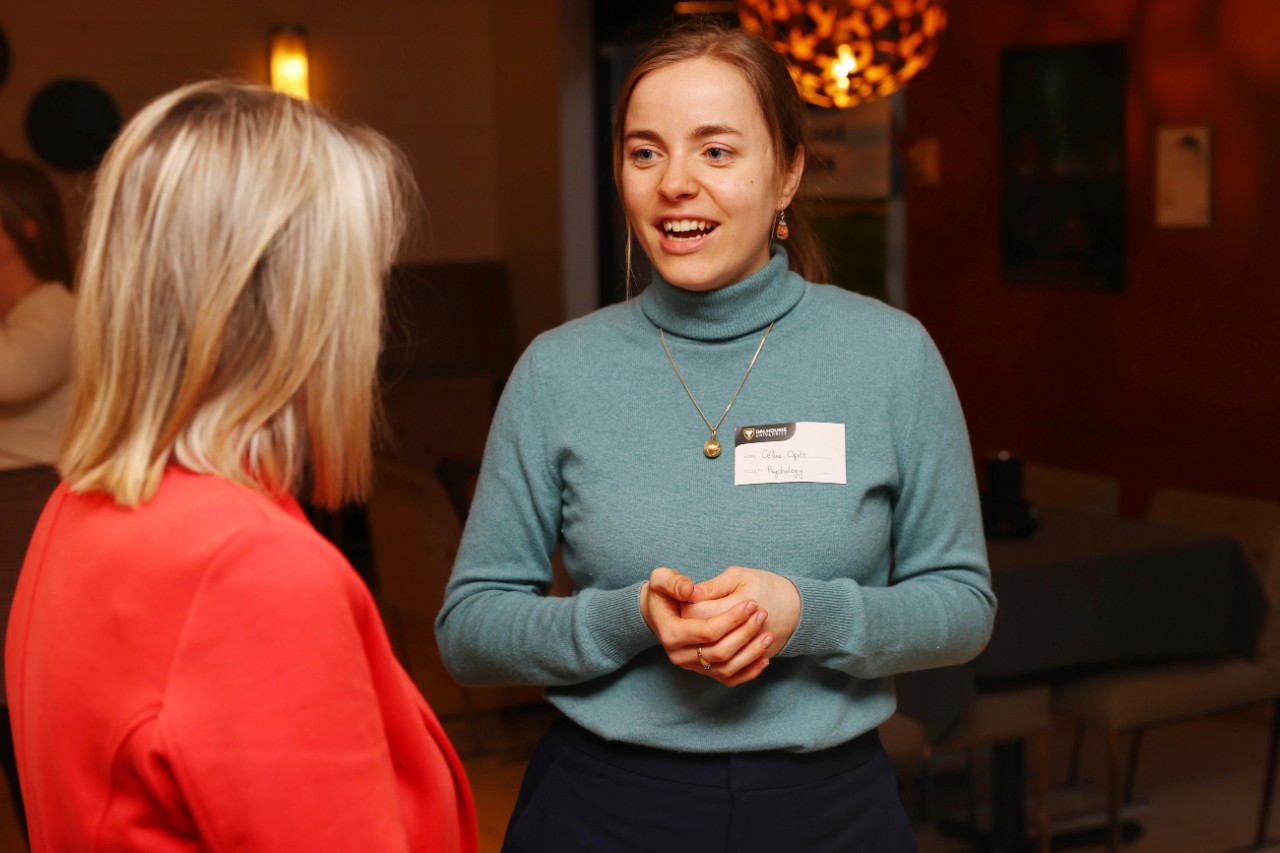 Celine Opitz standing with her hands clasped while speaking to a woman in a red jacket.