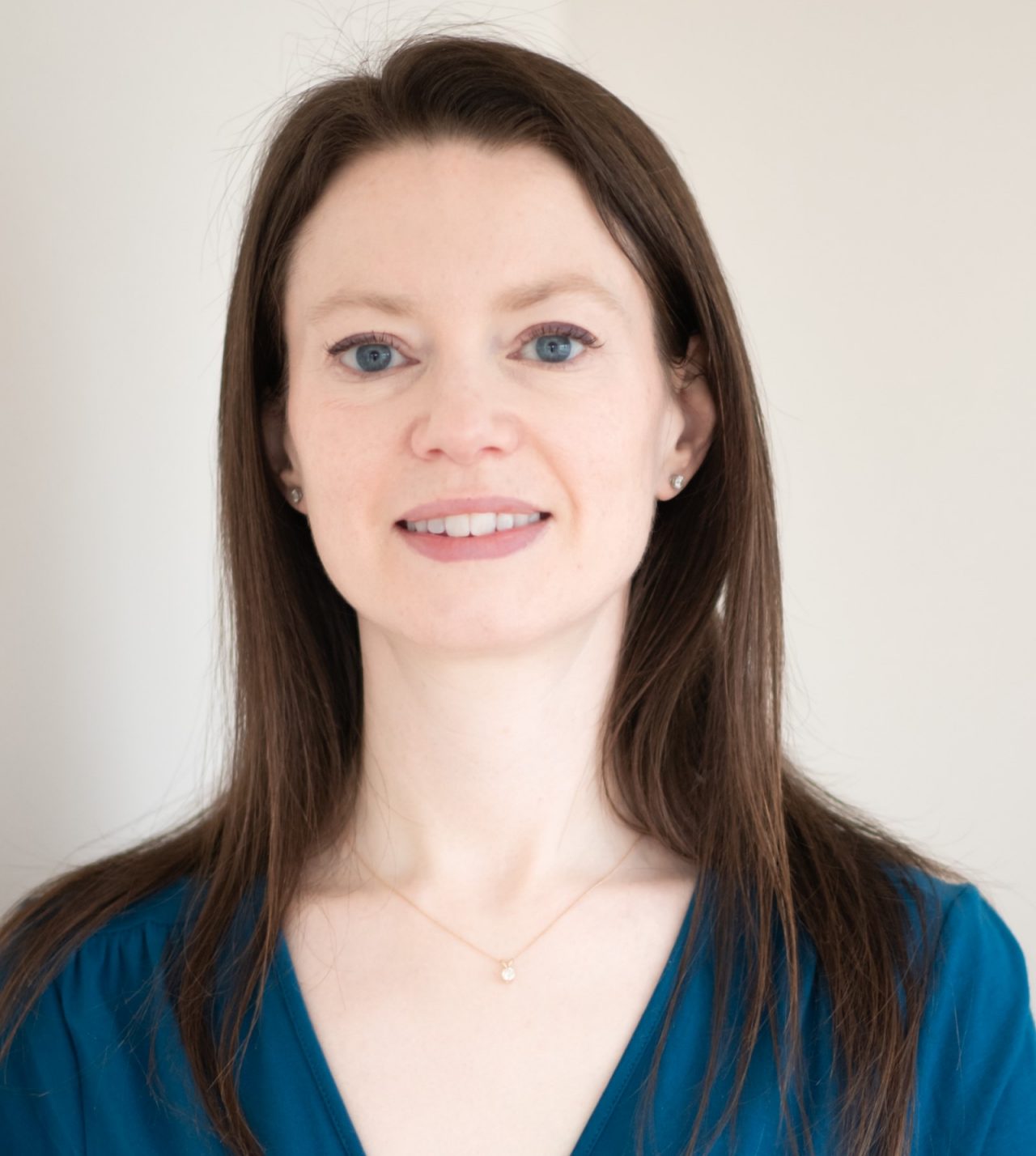 A white woman with shoulder-length brown hair smiles at the camera.