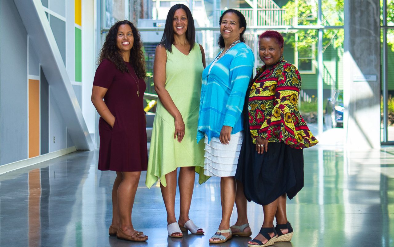 Four women stand side-by-side in the LeMarchant Place Atrium on the Dalhousie campus.