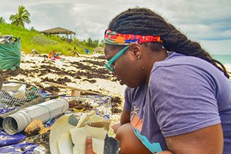 Kristal and others sort through plastic waste on a beach.