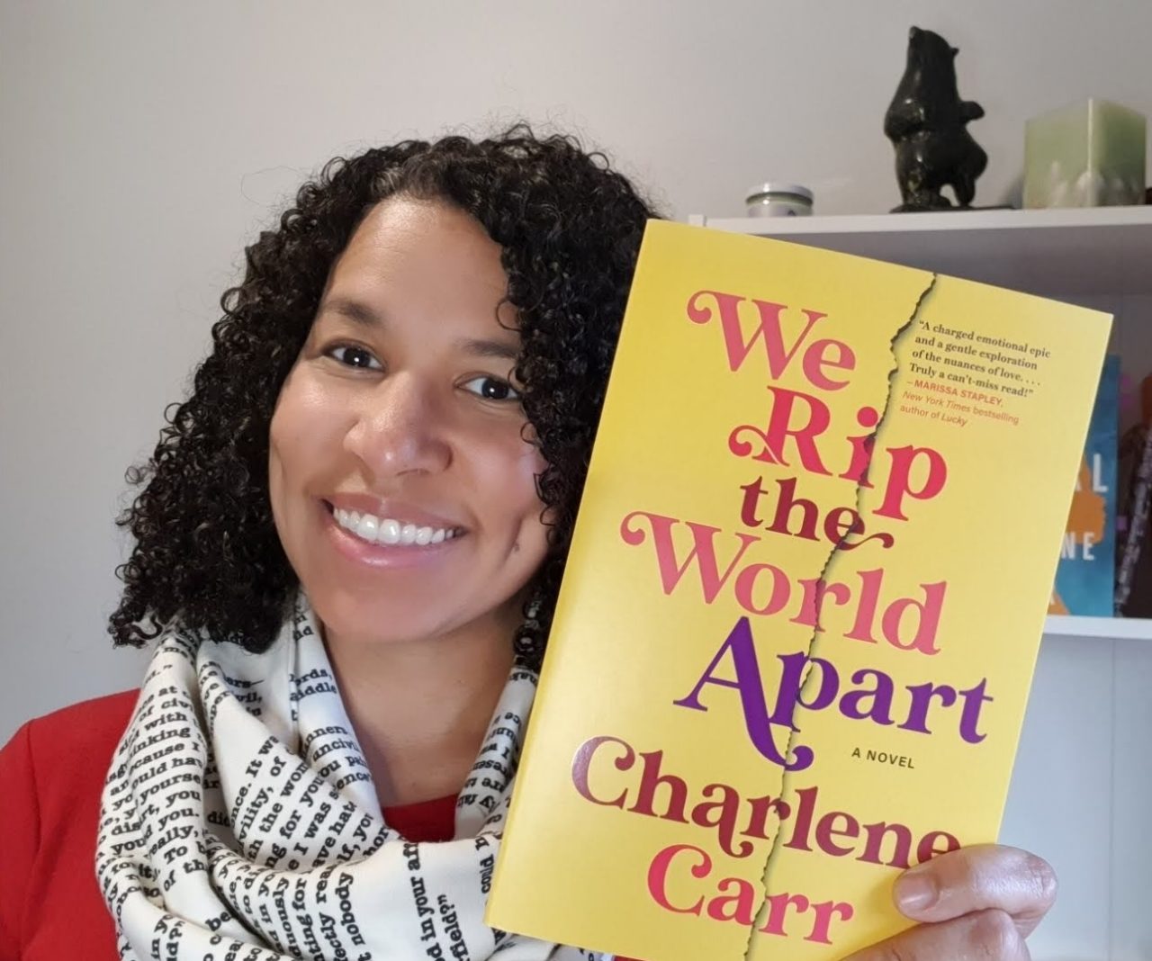 Carr holds up one of her books with a bookshelf in the background.