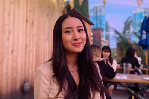 A female-presenting person smiling in an outdoor dining setting.