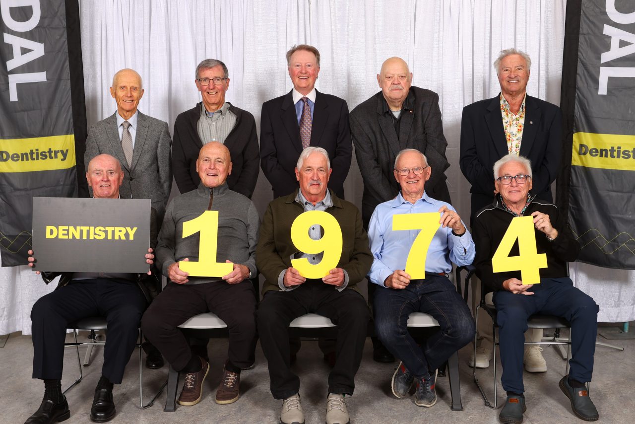 A group of ten men posing for a portrait at an event with the backrow standing and the front row seated.