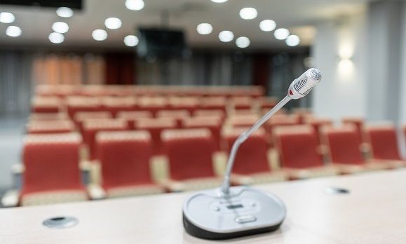 Microphone in front of a room full of empty seats.