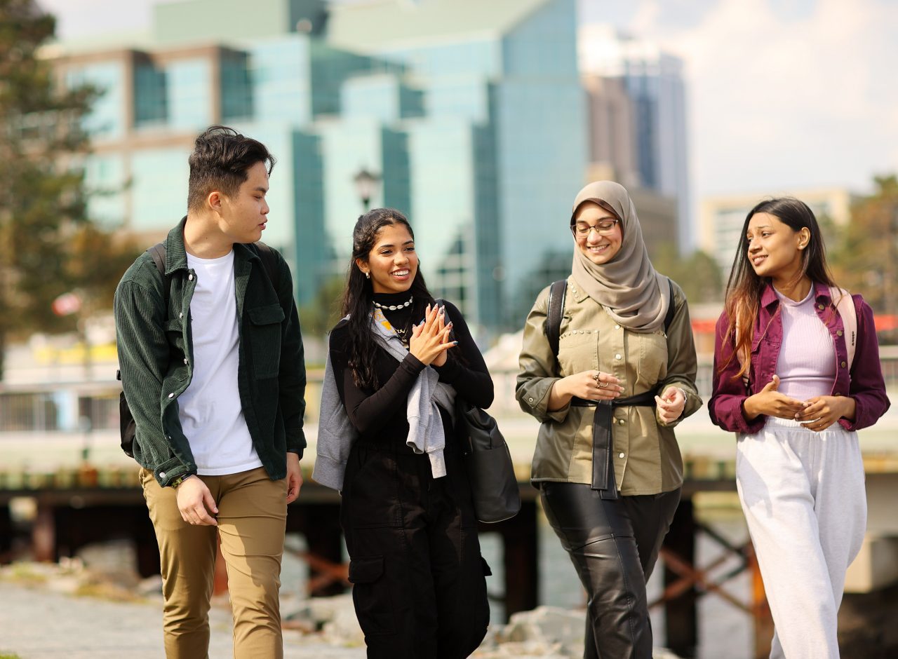 Four students walk on a path on the Halifax waterfront. 