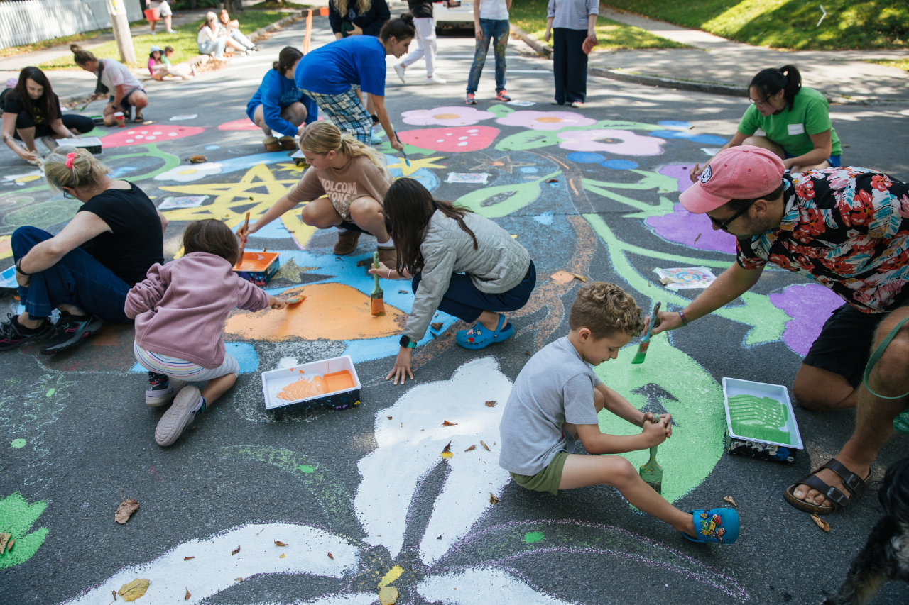 community painting a colourful mural on the street