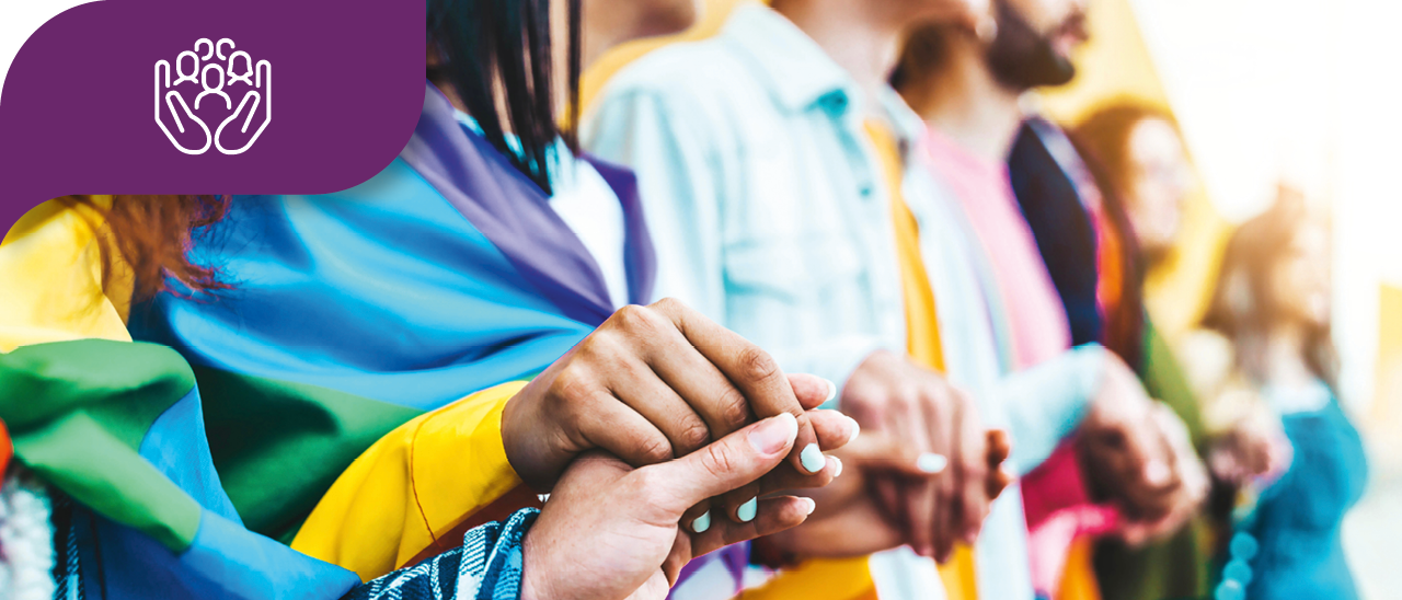 People holding hands, draped in a pride flag