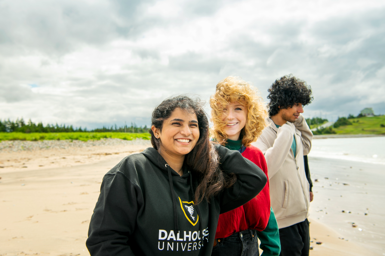 Three people standing on a beach with the wind blowing their hair